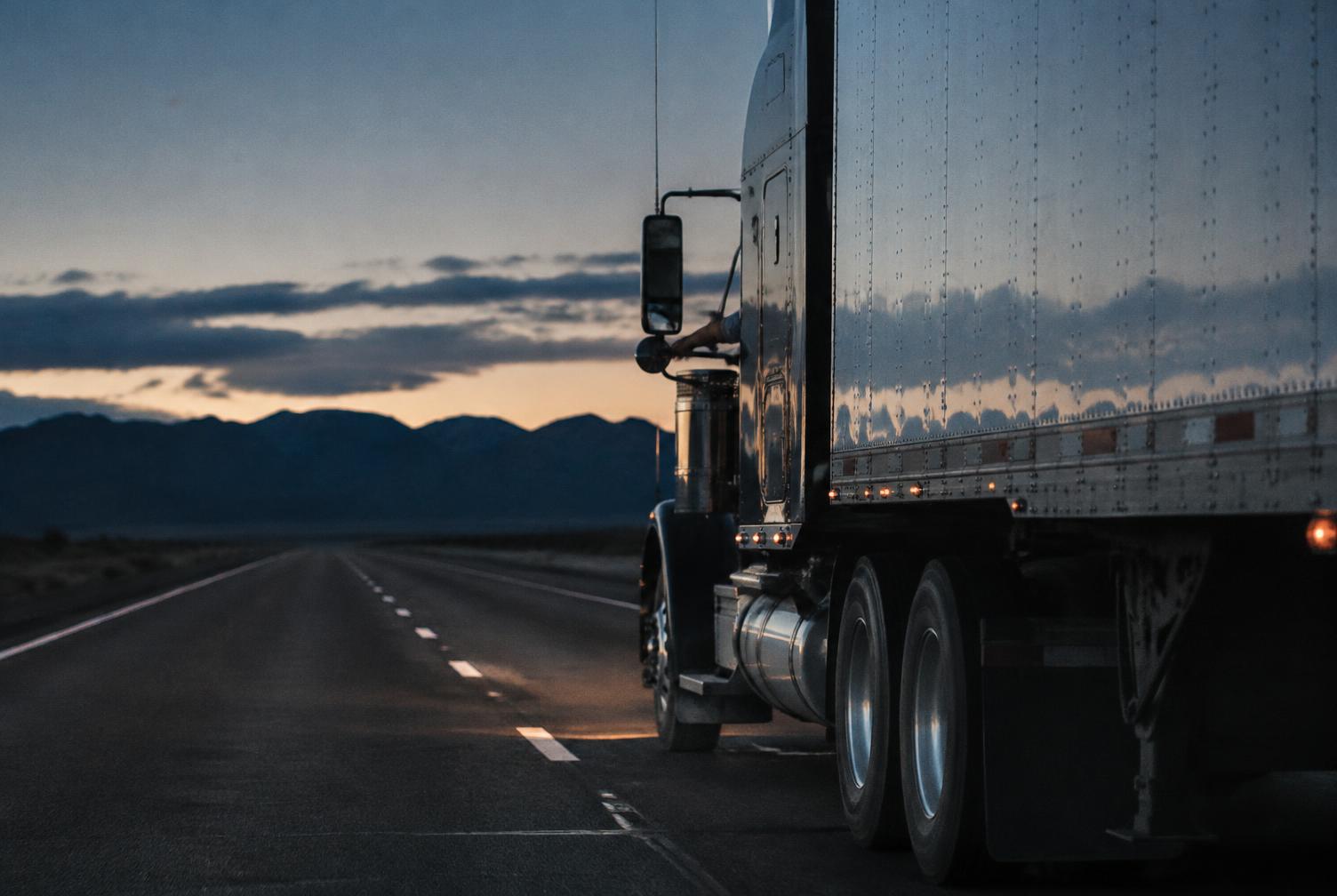 Semi truck on an open highway at dawn
